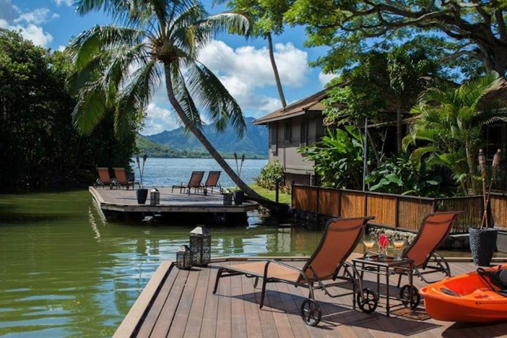 A sun patio on the water at one of the best resorts on the west coast that is surrounded by palm trees, with mountains in the distance