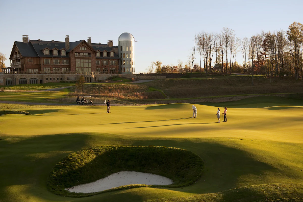 Hotel in the distance with people playing golf in the foreground in an article about the best resorts on the East Coast