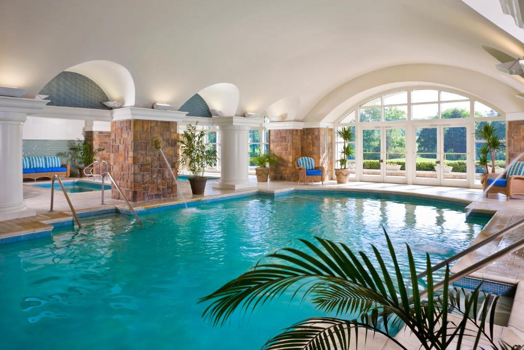 A spa type hotel pool with large arhed windows and plants surrounded the water. the article is about the best resorts on the East Coast