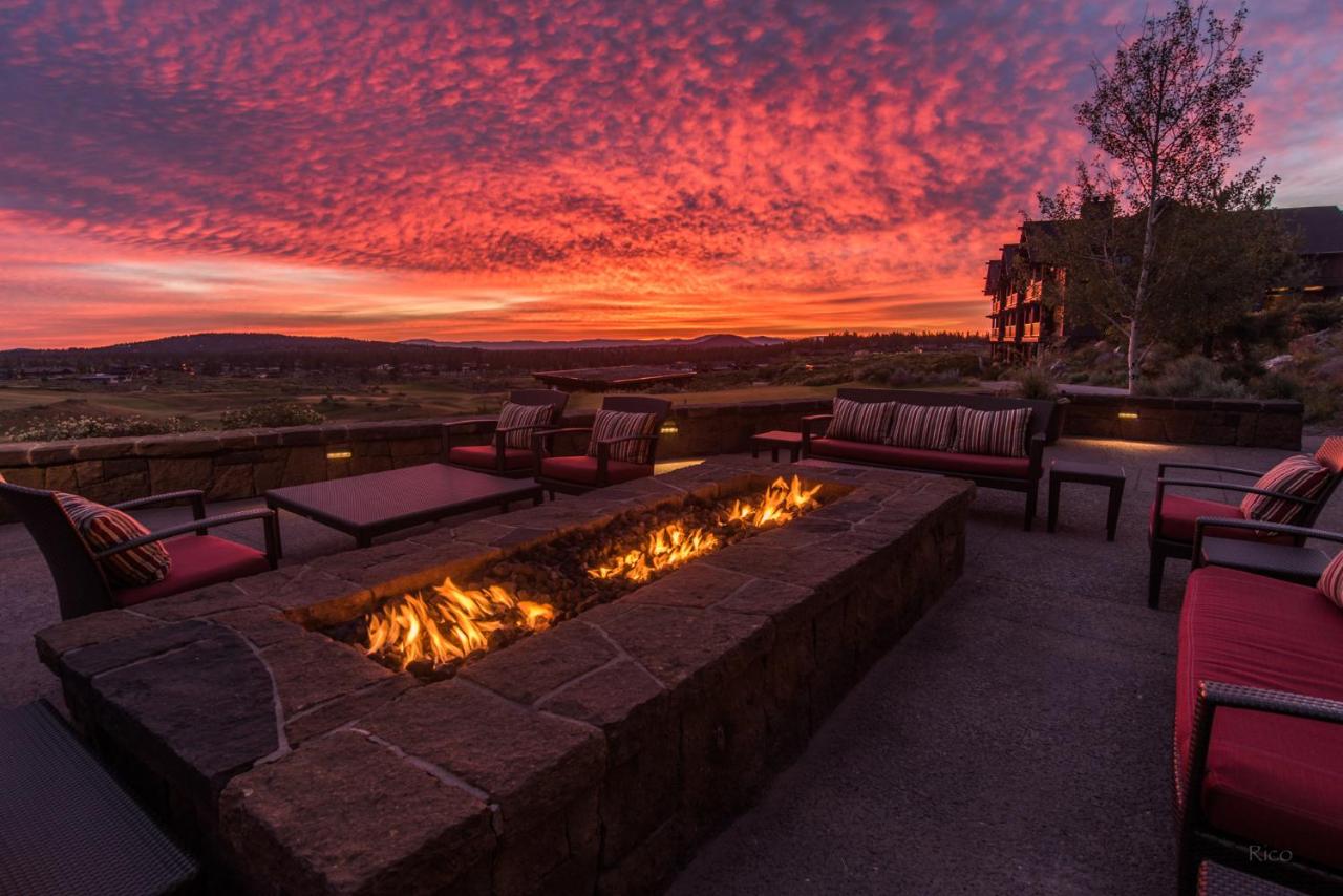 The view from a stone terrace on the side of a mountain at sunset with a long firepit on it