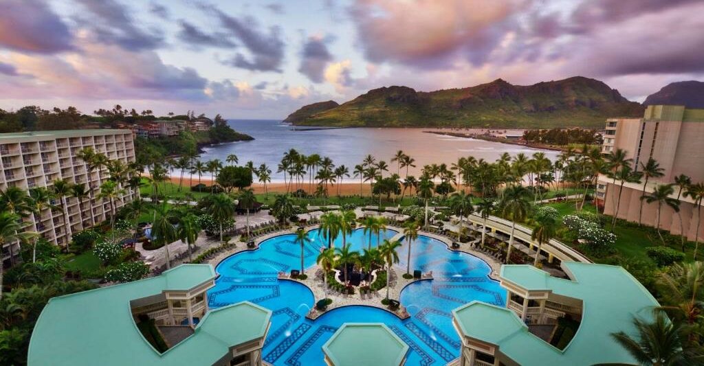 The view of a large pool and a beach with mountains on an island at one of the best resorts on the West Coast