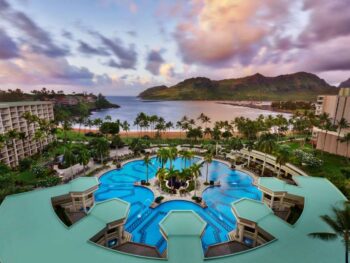 The view of a large pool and a beach with mountains on an island at one of the best resorts on the West Coast