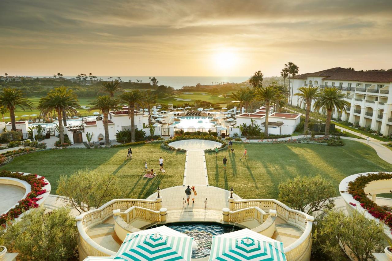 The view of a green lawn, several pools, palm trees, and water in the distance at one of the best resorts on the West Coast