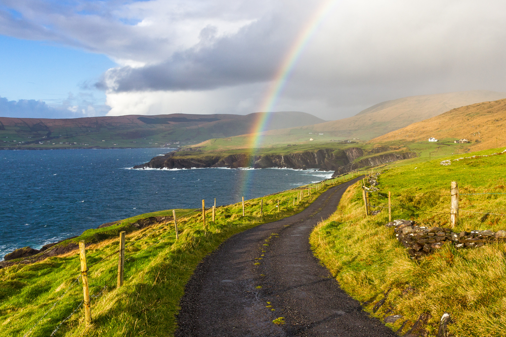 A road following the shore with a rainbow overhead during a trip to Ireland.