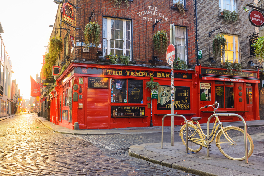 Early morning at the iconic Temple Bar with many hanging plants and red paint in Dublin, Ireland.