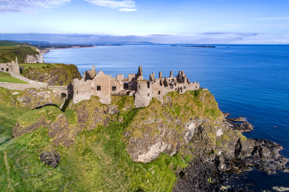 Ruins of Dunluce Castle on a rugged cliff above the sea in Northern Ireland.