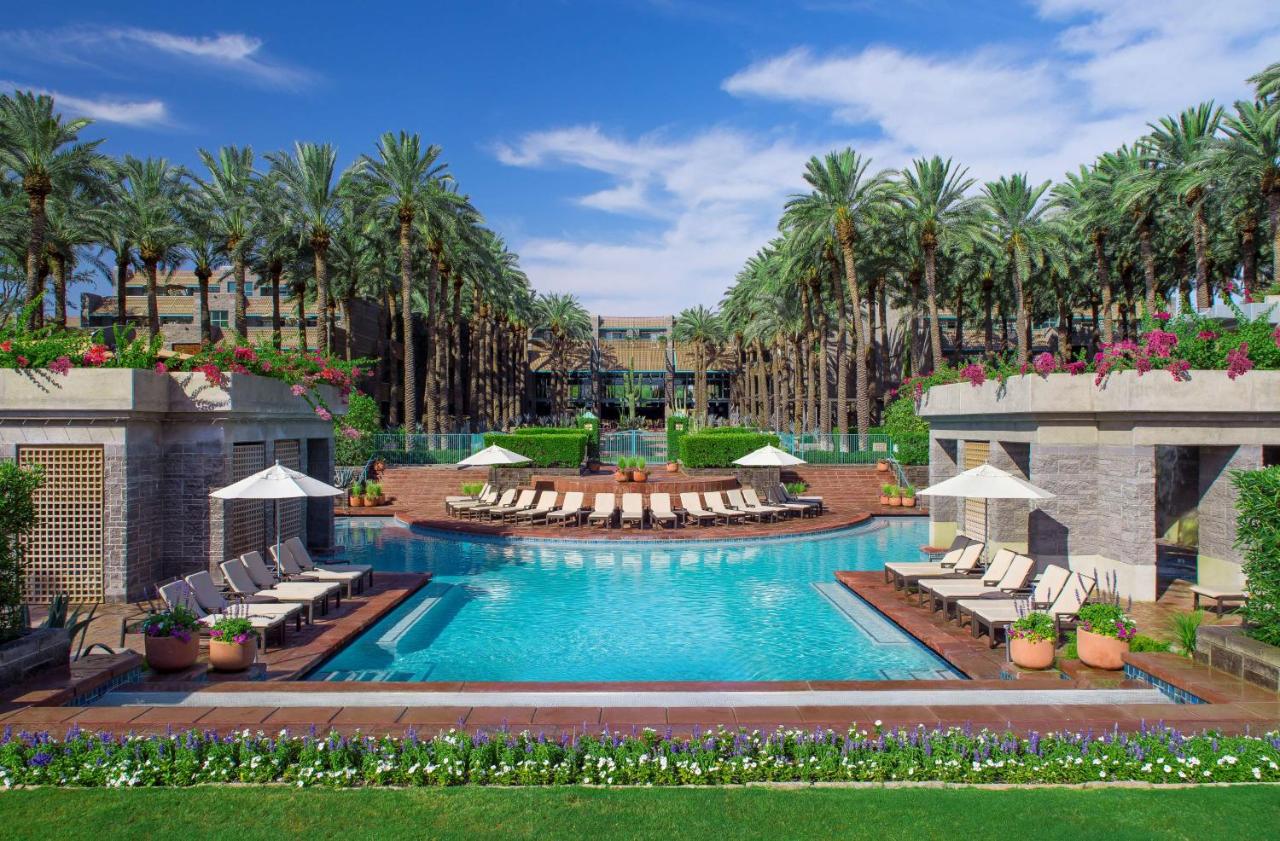 one of the best resorts in Arizona, the Hyatt Gainey Ranch with one of its pools and many palm trees framing the resort facade. 