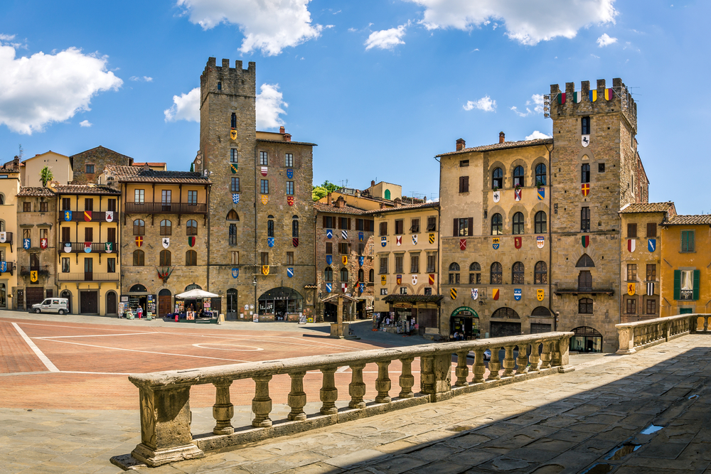 The plaza in Arezzo with flags hanging from the windows of the old buildings.