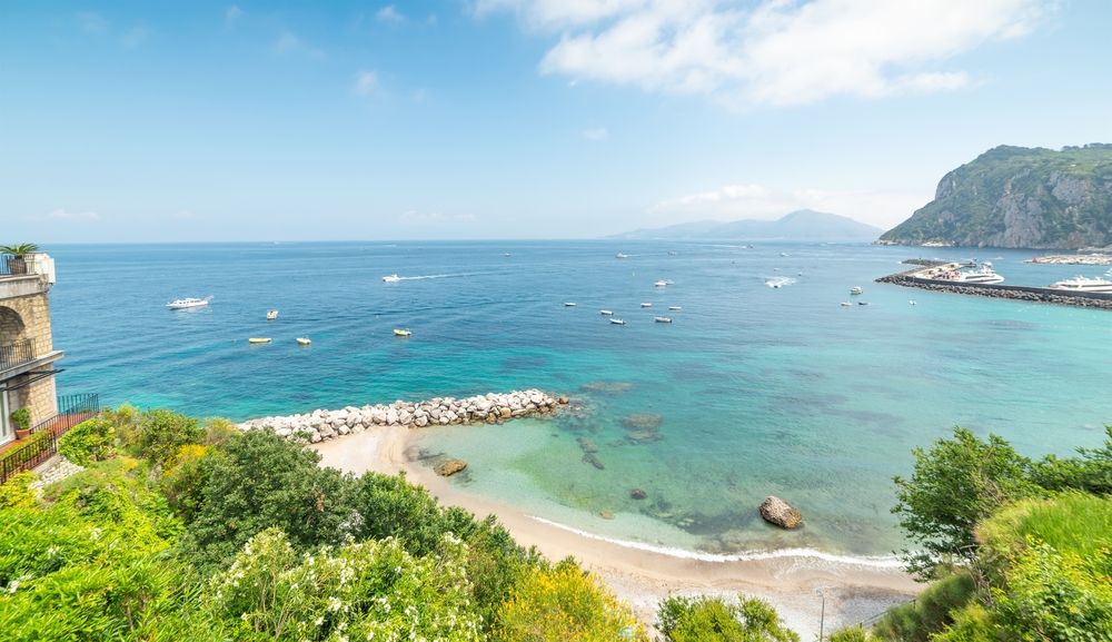 An above view of Marina Grande Beach, one of the best beaches in Italy, with soft sand and shallow blue water with some small boats.