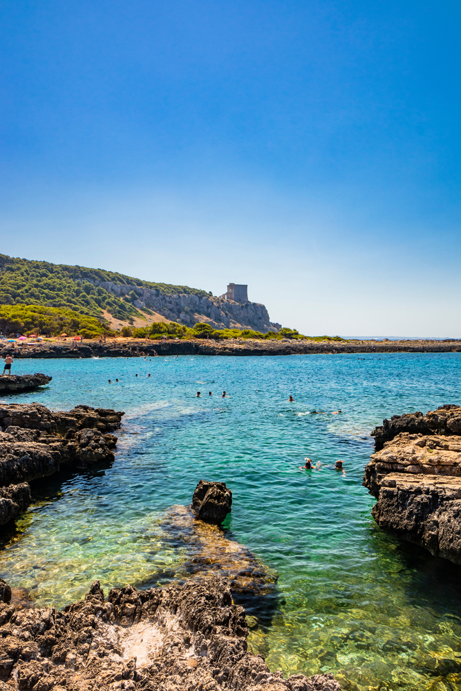 People swim amongst the rocks of the wild beach at Porto Selvaggio nature preserve.