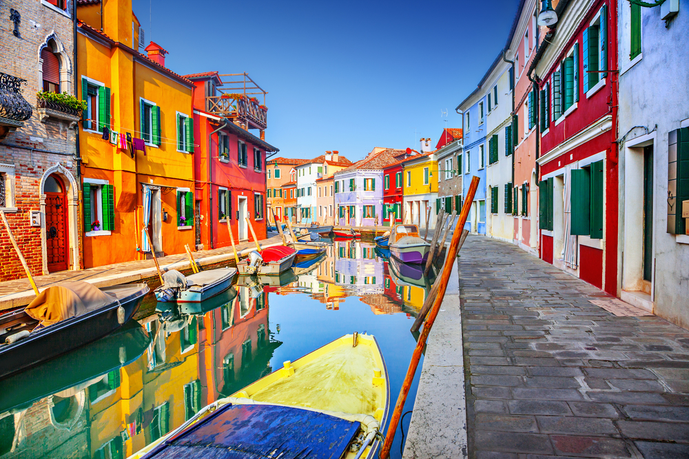 Canal in Burano with boats surrounded by colorful buildings.