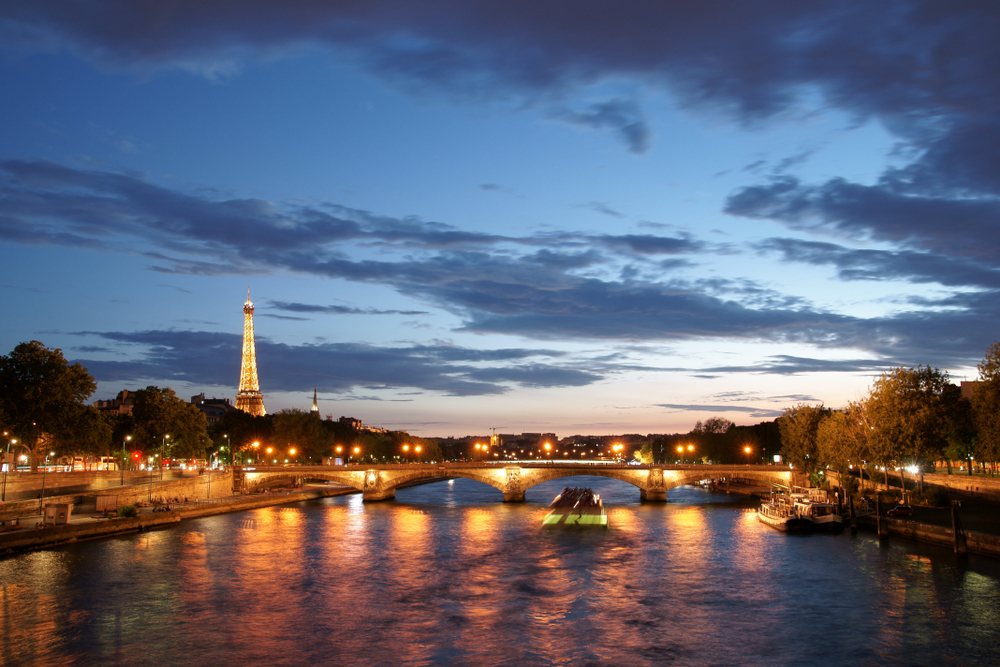Dusk over the River Seine with a lit up bridge and the Eiffel Tower.