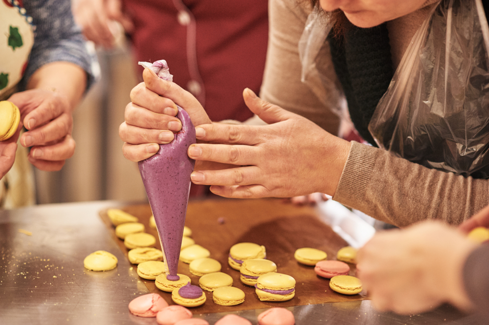 A group of people work on icing and putting together macarons.