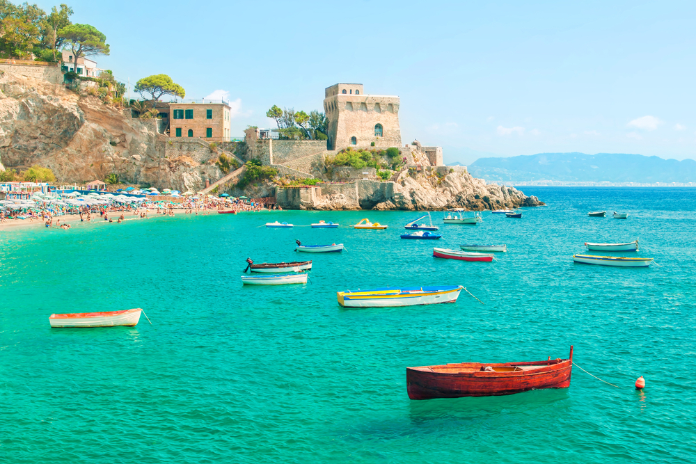 Small, colorful boats dot the water off the beach in Erchie near the old castle.