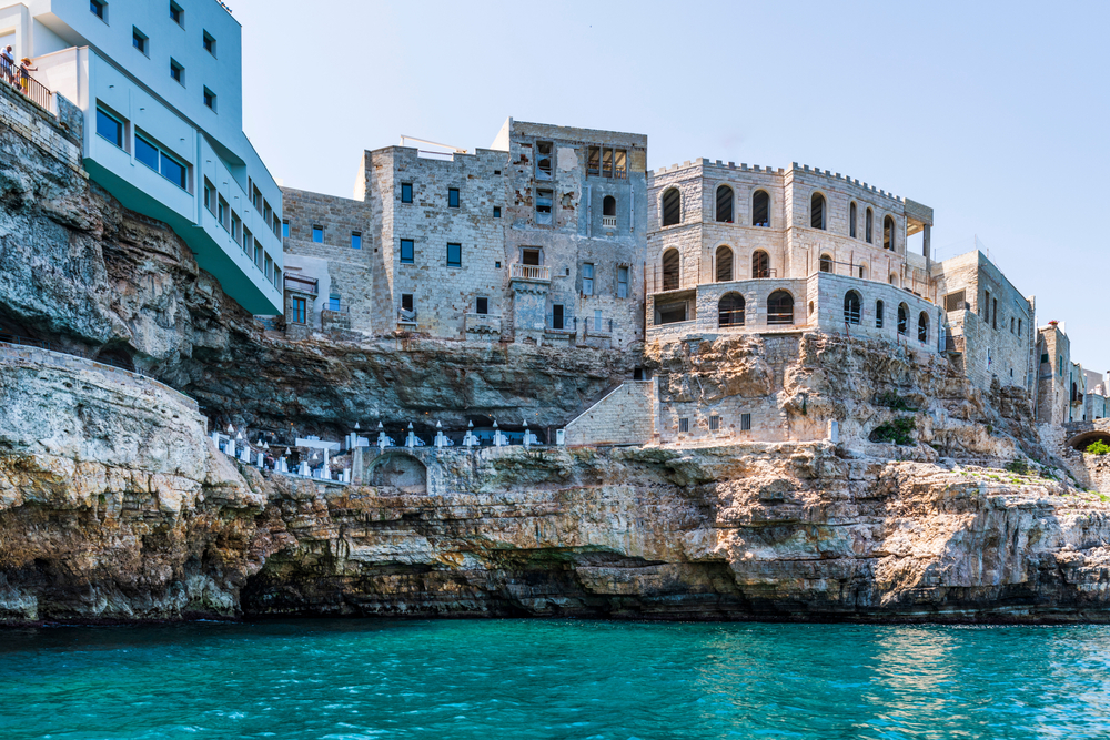 View from the water to the cave restaurant below old buildings.