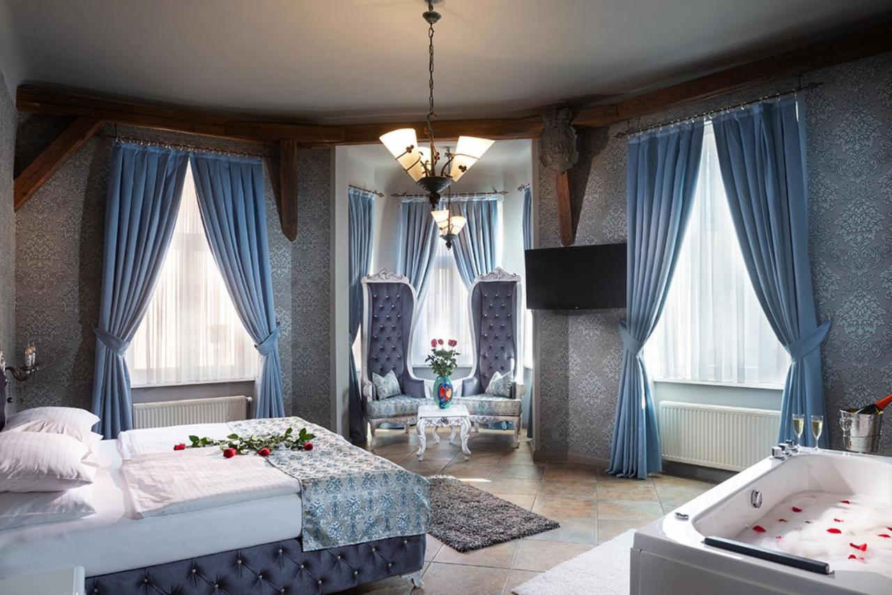 Plush, blue room with bed, big curtains, and bathtub.