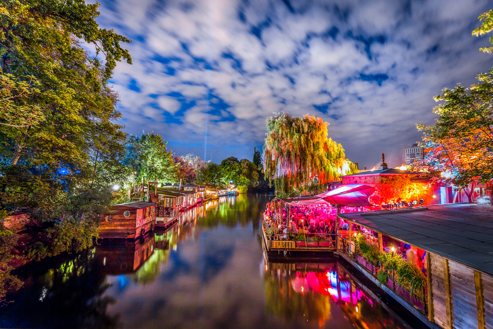 Open air nightclub with colorful lights beside the river at night.