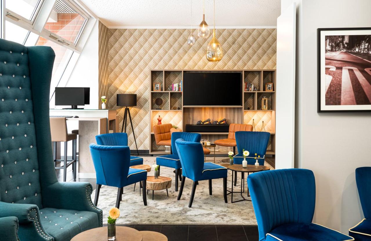 Lounge area in the Leonardo Hotel with many blue chairs and a TV.