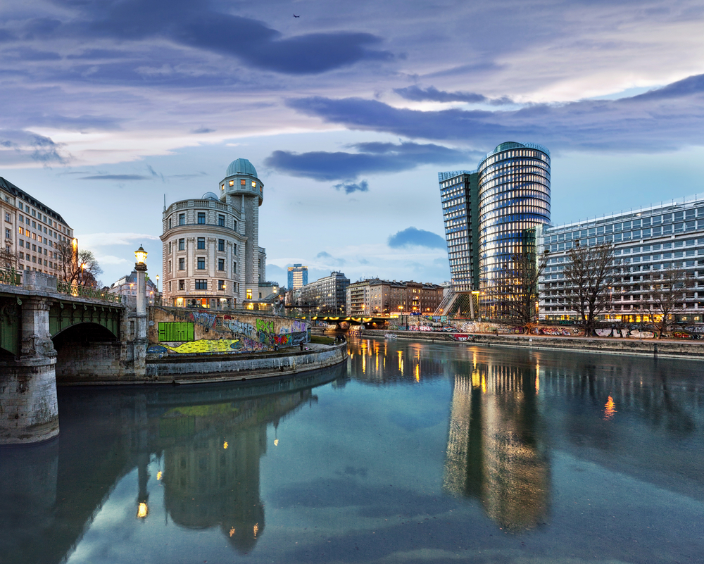 Sunset over the Danube Canal with a mix of historic and modern buildings.