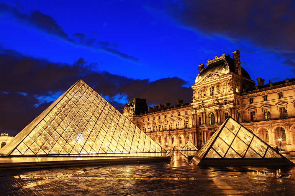 The iconic glass pyramids lit up in front of the Louvre.