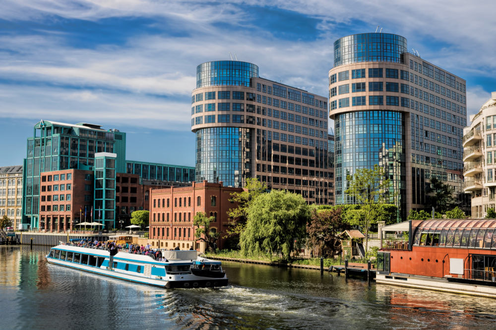 Cruise boat in the river near modern apartment buildings.