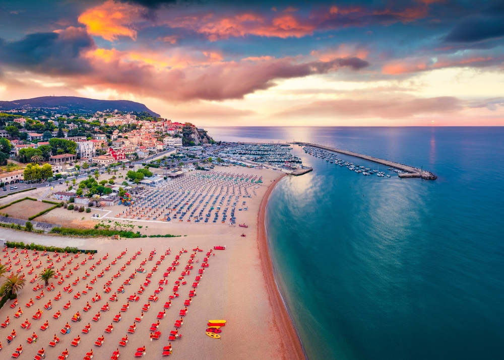 Aerial view of the sunset over the beach in with many beach chairs.