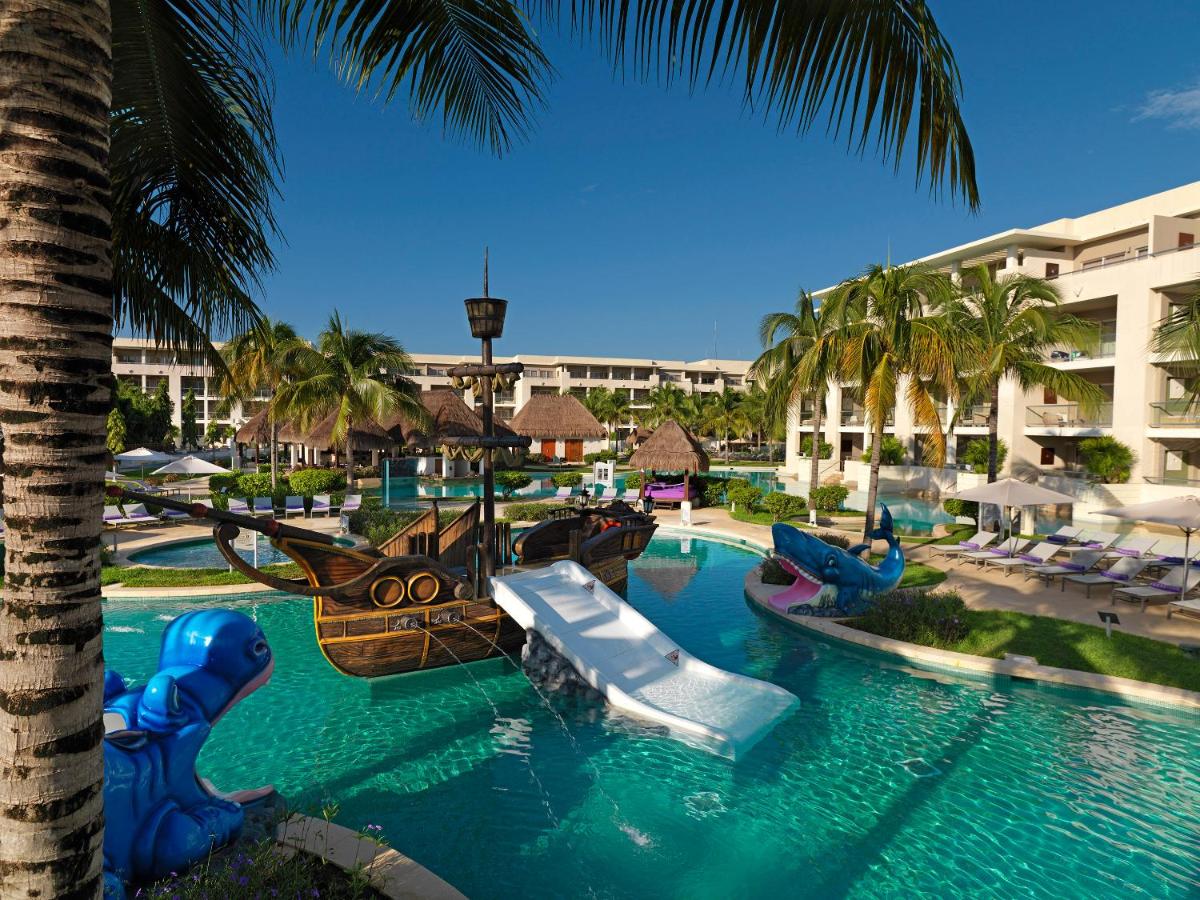 A pirate ship with a slide and other things in a pool surrounded by palm trees 