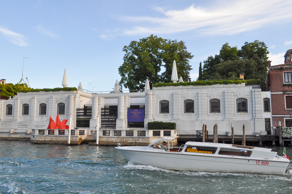 View from the water of the Peggy Guggenheim Collection with a boat in the canal.