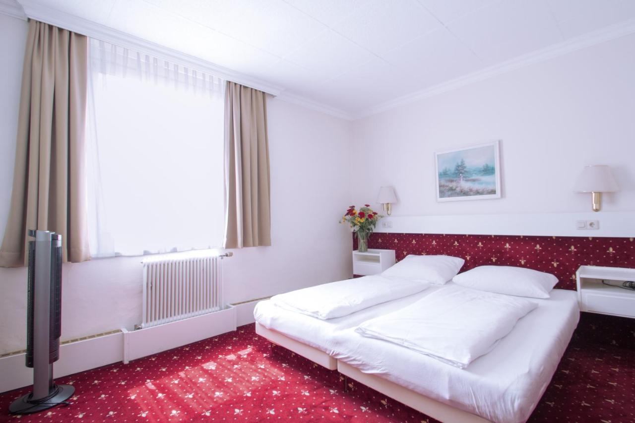 Simple hotel room with a bed and window.