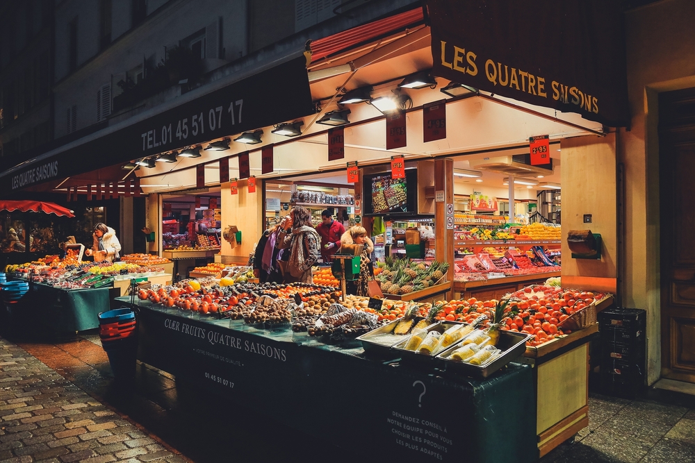 A store with fresh vegetables and fruit at night on Rue Cler.