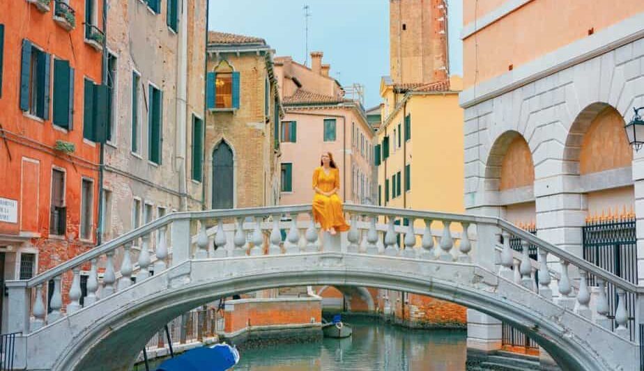 Woman sitting along a canal during her 2 days in Venice itinerary.