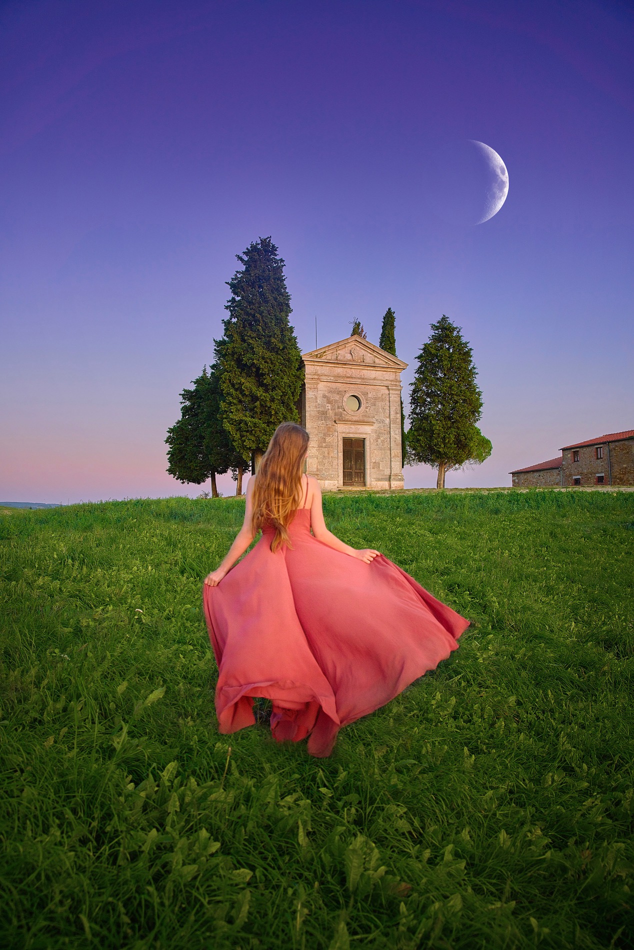 Woman in flowing pink dress walks tower a temple at dusk in Tuscany.