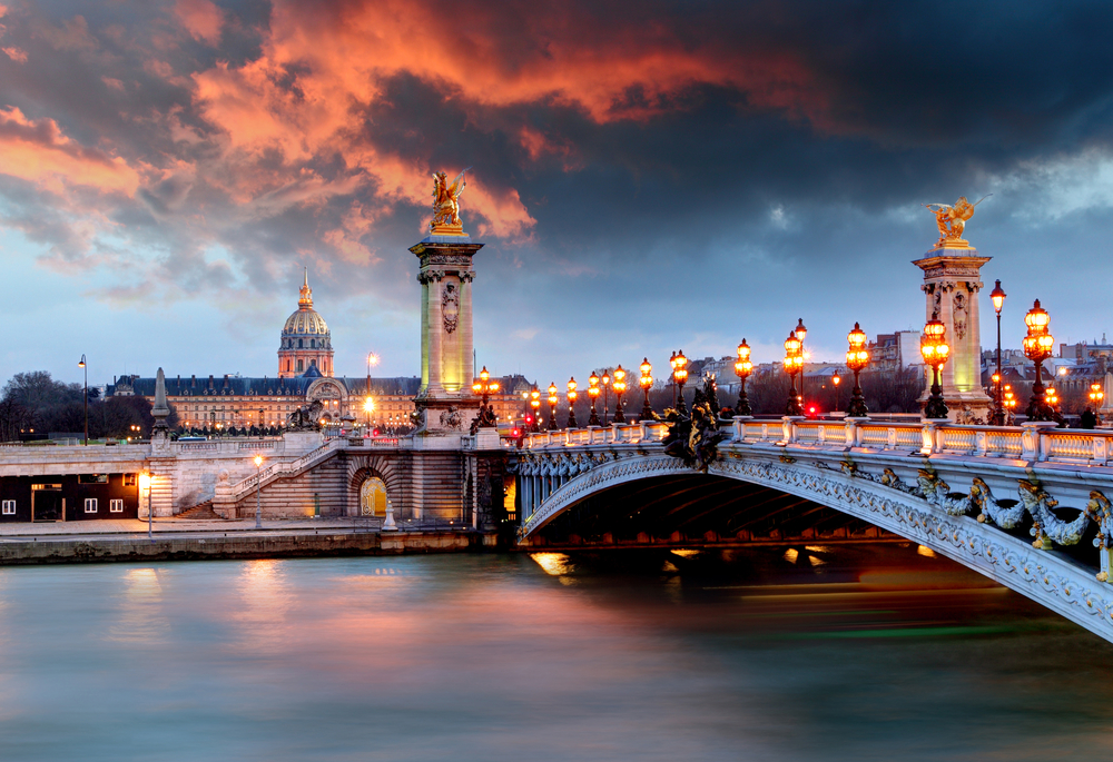 Vivid sunset over the Pont Alexandre III with the river reflecting the colors.