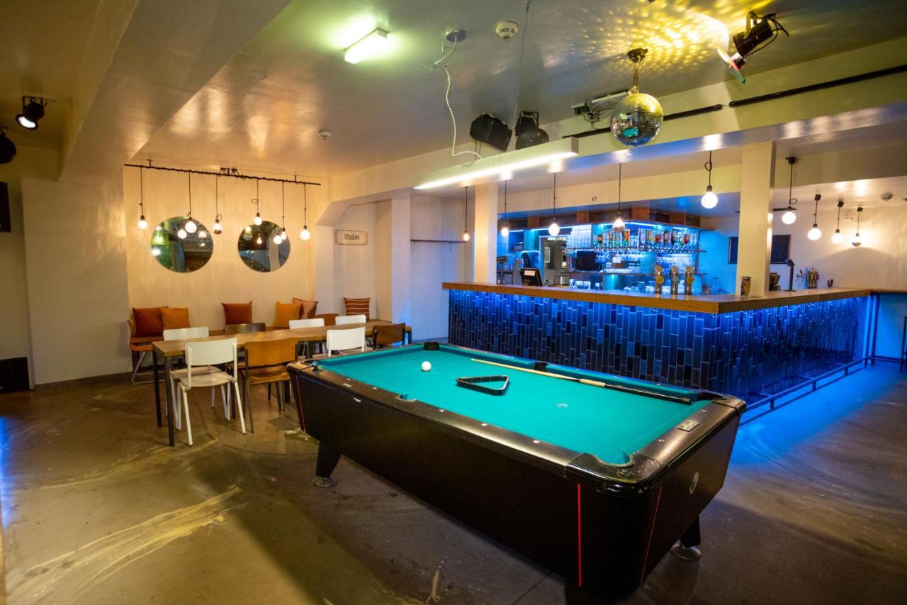 Pool table and bar in a room with colorful lights.