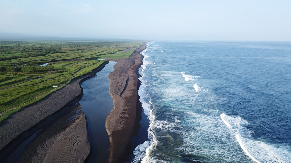 Khalaktyrsky Beach is one of the best beaches in the world with its dark, black sand, perfect surfing waves, and green Russian coast! 