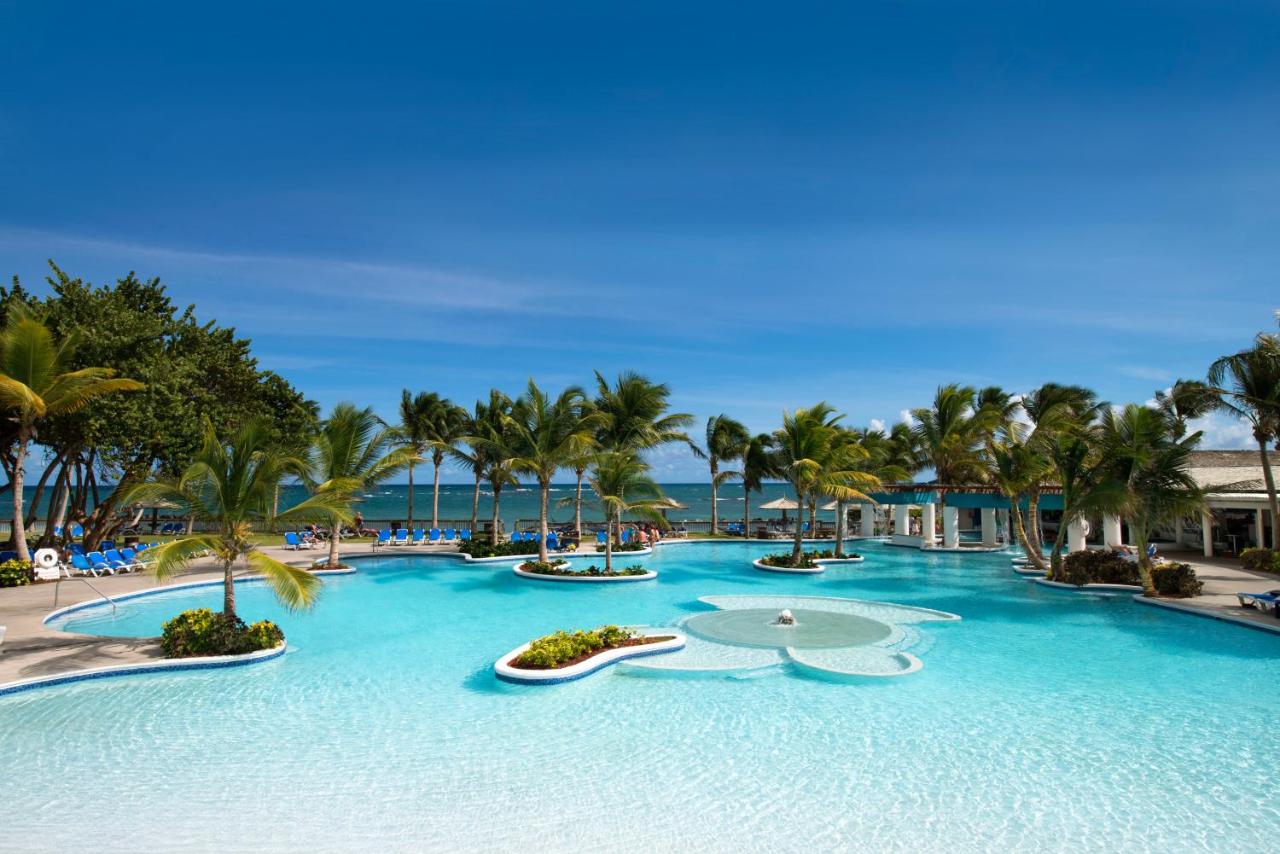 A large pool surrounded by palm trees on the edge of the ocean at one of the best all inclusive resorts for families