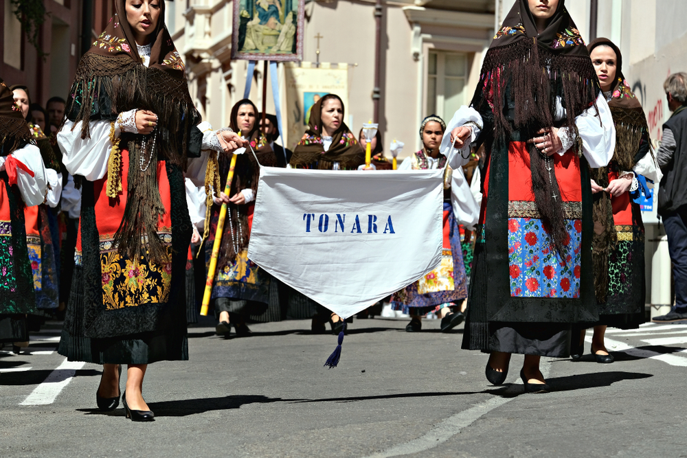 A group of people walk down the street in religious dressings in Italy in May, celebrating the Festa di Sant'Efisio.