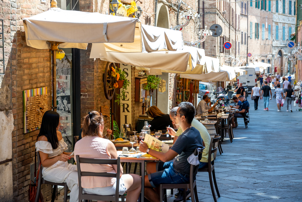 Smaller crowds, as seen in this photo where only a few tables are full and in use on a strip of restaurants, are typical during the shoulder season.