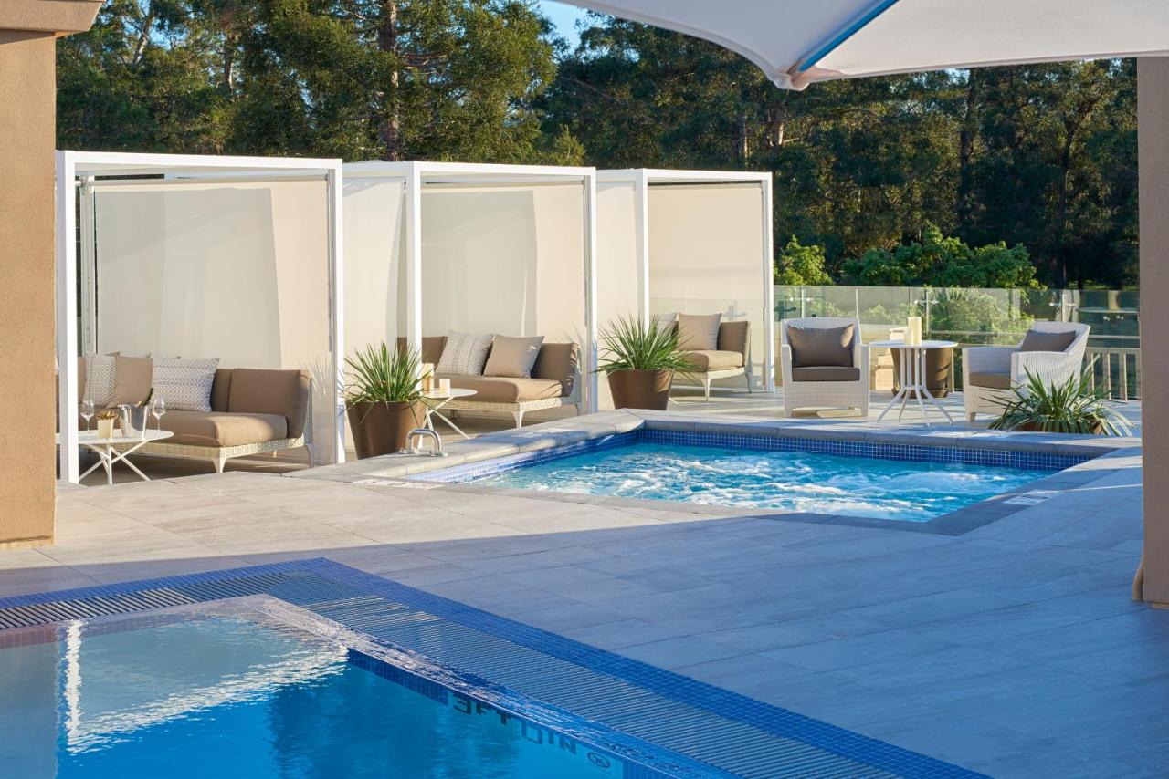 The view of a pool and hot tub with private cabanas around it