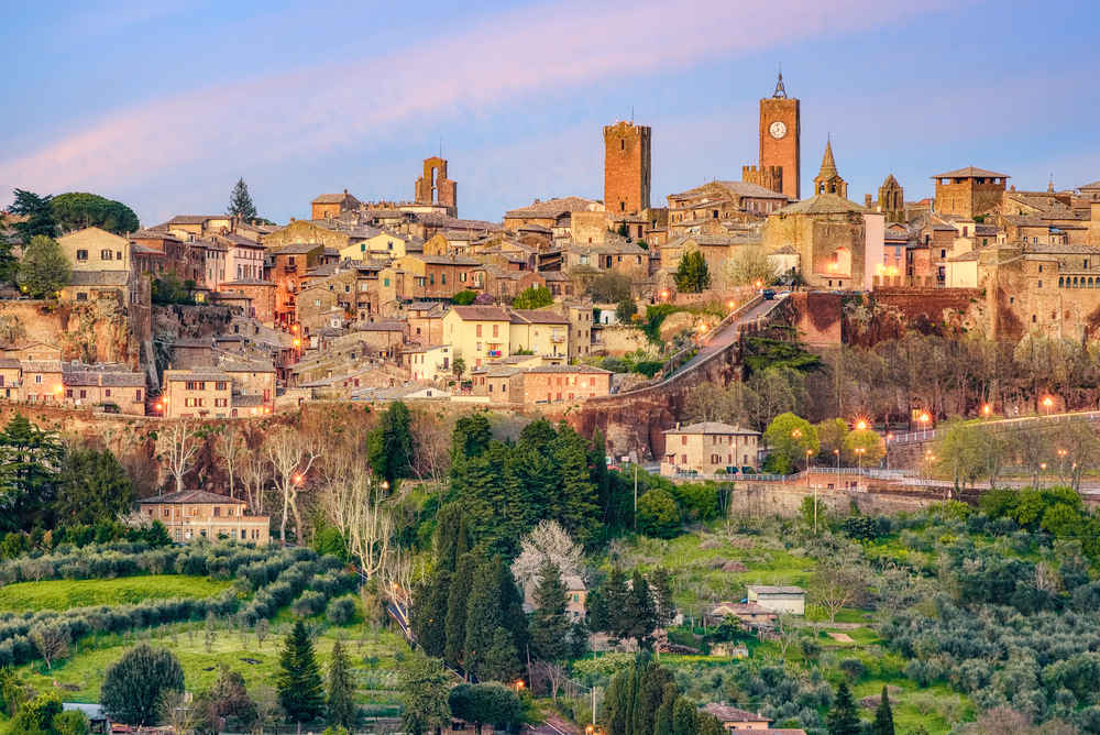 The historic hill-top town of Orvieto with green hills in the foreground.