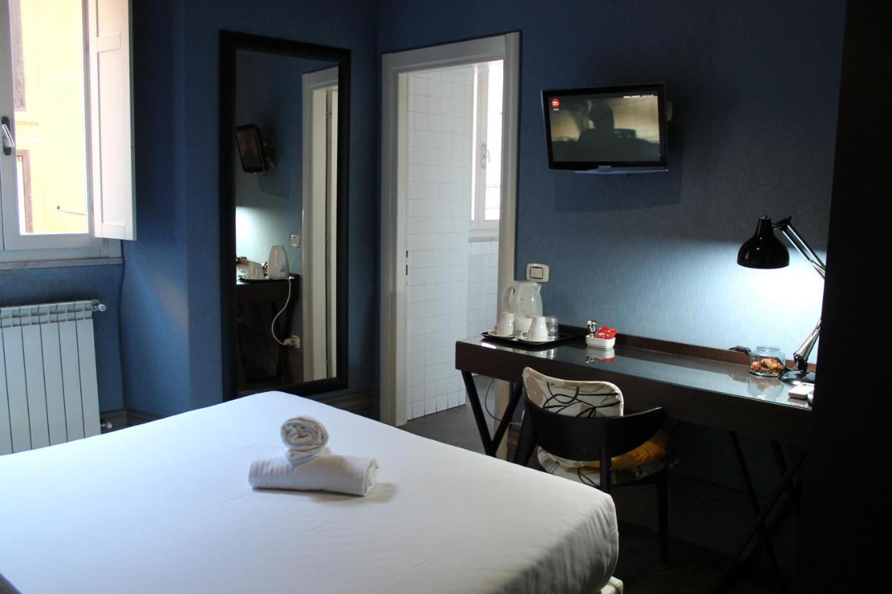 Simple hotel room with bed, table, and mirror.