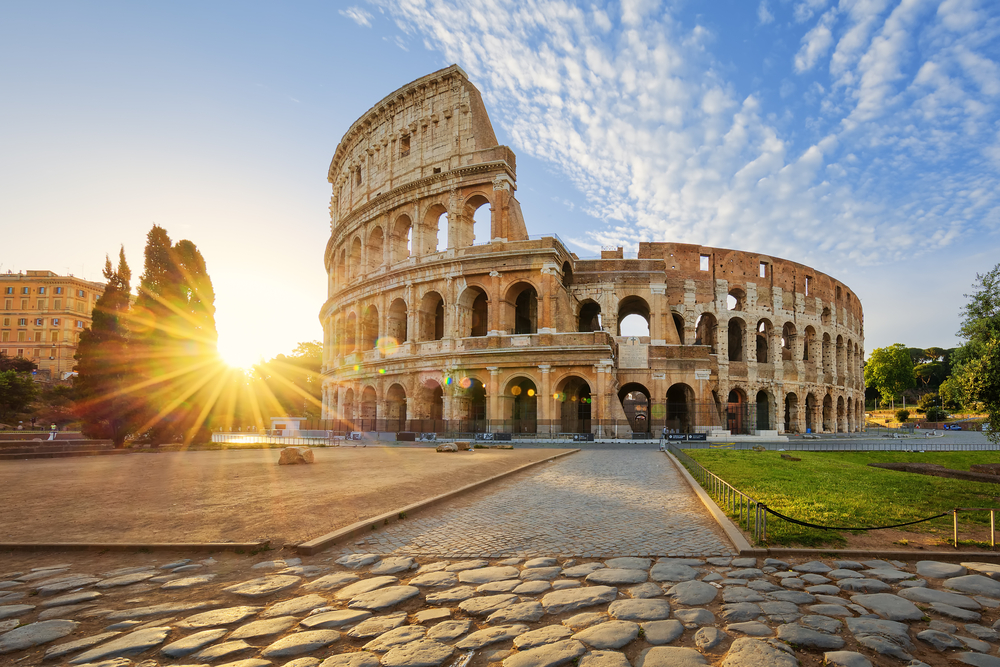 View of Colosseum in Rome and morning with sun streaming into the picture. 