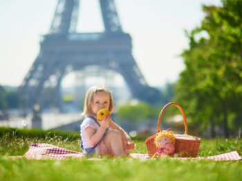 child in paris sitting in front of tower eating an apple