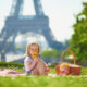 child in paris sitting in front of tower eating an apple