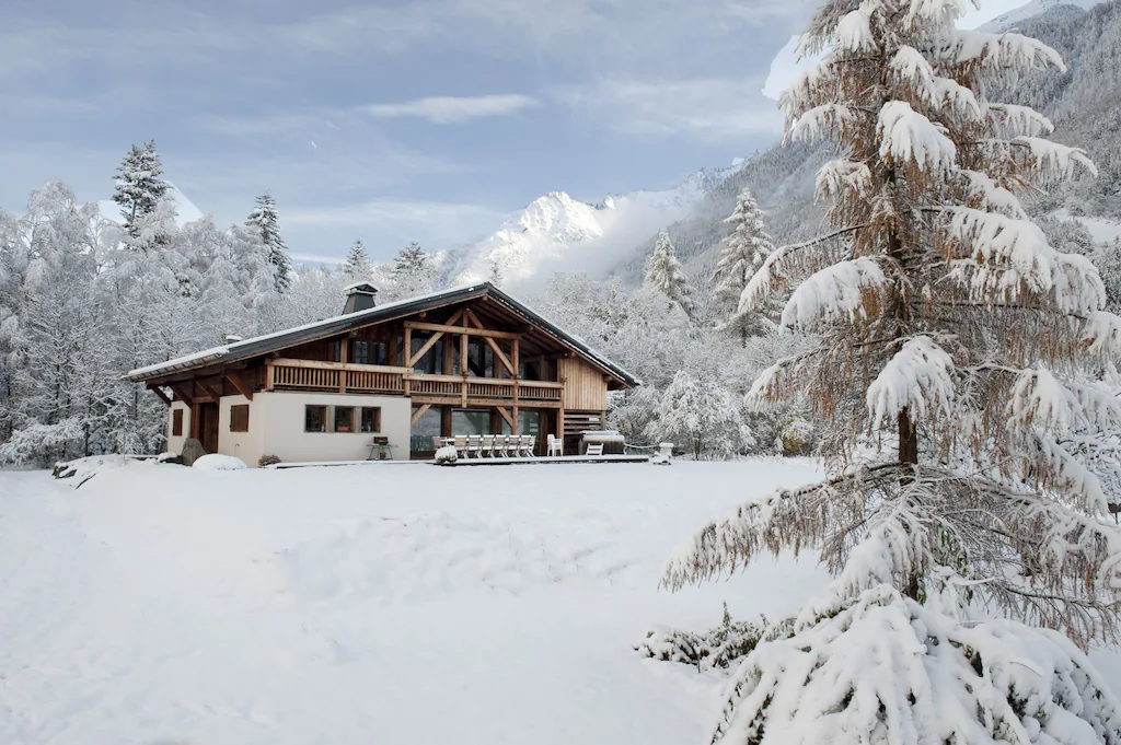 View of an adorable chateau in the snow with mountains in the background. 