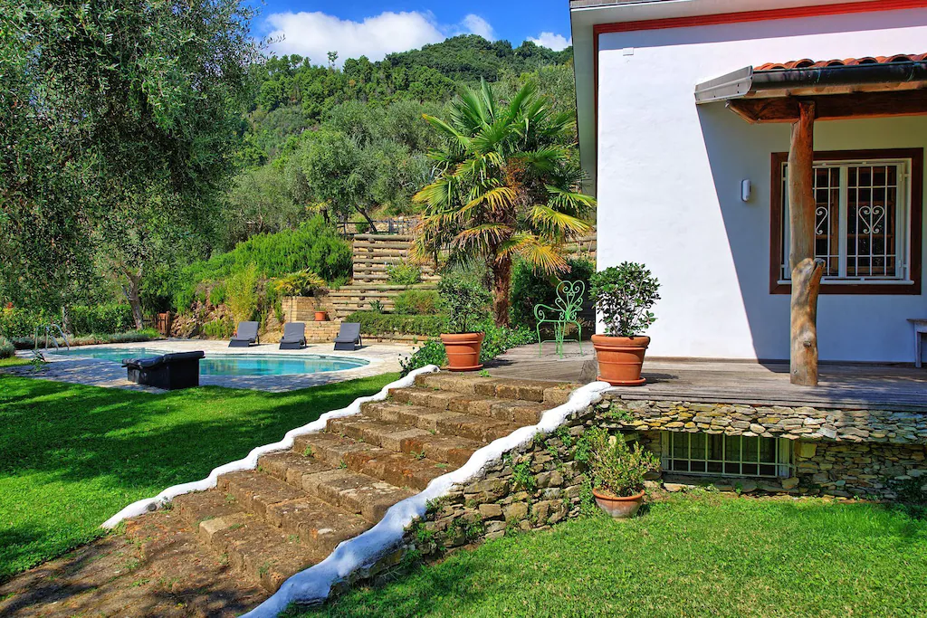 View of the whitewashed house and pool of Villa Oliveta in Italy. This is one of the best Airbnbs in Tuscany. 