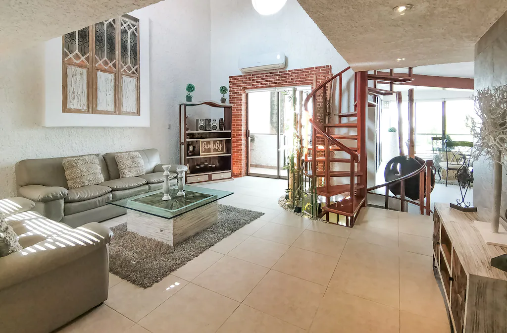 View of the spacious living room and spiral staircase of the Cancun Luxury Residence. This is one of the best luxury airbnbs in Mexico.