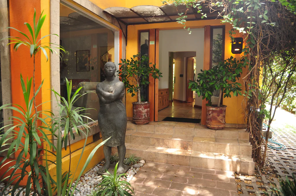 View of the colorful orange exterior and welcoming front door of the lush jungle home of the Oasis in Mexico city, one of the best airbnbs in Mexico City.