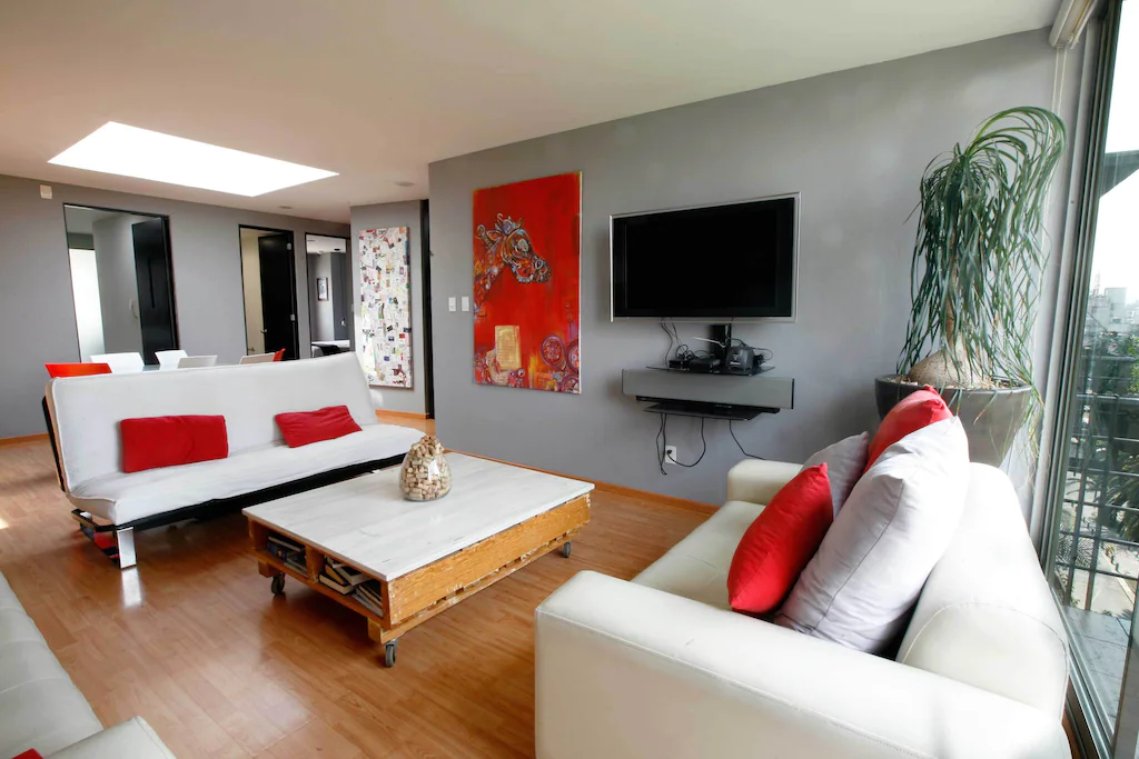 View of the cozy living room with a skylight and beautiful houseplant at the La Roma Apartment, one of the best airbnbs in Mexico. 