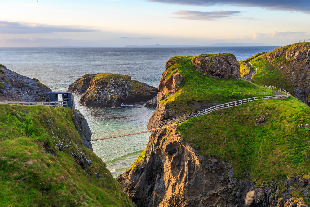 Sunset aerial view of the Carrick A Rede Rope Bridge along the ocean.